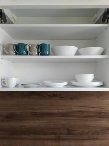 a shelf with cups and saucers on it at Lagan Apartament in Będzin