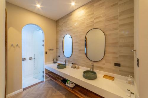 a bathroom with two sinks and a shower and two mirrors at Luxury villa on the Cloud Forest Infinity Pool in Monteverde Costa Rica