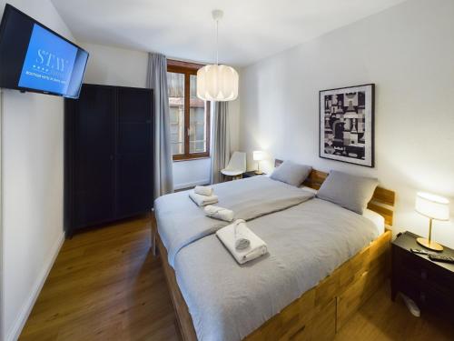 a bedroom with a large bed with a tv on the wall at Cocon by Stay Swiss - 1 bedroom apartments in old town in Porrentruy