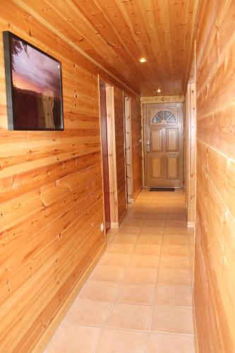 - un couloir avec un mur en bois, une télévision et une porte dans l'établissement T3 Villard de Lans, à Villard-de-Lans