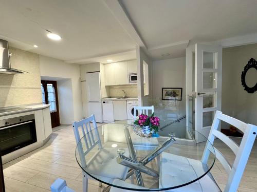 a dining room with a glass table and white chairs at Casa Tía Milagros in Puebla de Sanabria