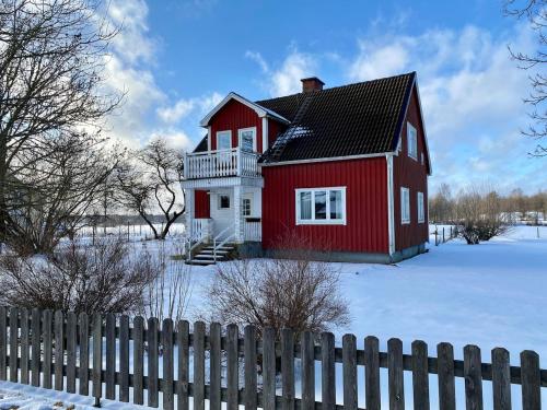 a red house in the snow with a fence at Fully equipped country house with lake location in Eksjö