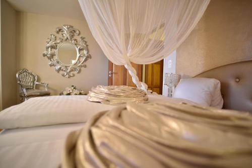a bedroom with a bed with white curtains and a mirror at Schloss Wartensee in Rorschacherberg