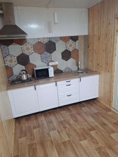 a kitchen with white cabinets and a tile wall at Villa Opir in Skole