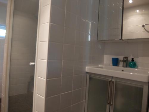 a white tiled bathroom with a sink and a shower at Holiday home Giethmen in Giethmen