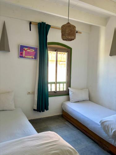 two beds in a room with a window at Atlantic Hostel in Essaouira