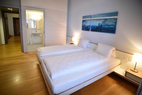 a large white bed in a room with a bathroom at Schloss Wartensee in Rorschacherberg