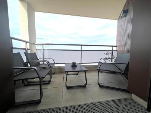 - un balcon avec des chaises et une table basse dans un bâtiment dans l'établissement Brand new, fully equipped, comfortable apartment, à Giberville