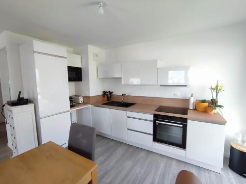 une cuisine avec des armoires blanches et une table en bois dans l'établissement Brand new, fully equipped, comfortable apartment, à Giberville