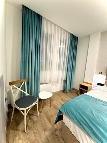 a bedroom with a bed and a chair and a window at Alegria Rooms Sarajevo in Ilijaš