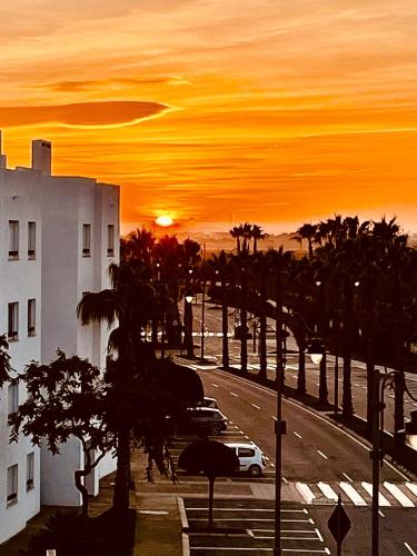 a sunset over a street with palm trees and a building at Atico Miso in Torre-Pacheco