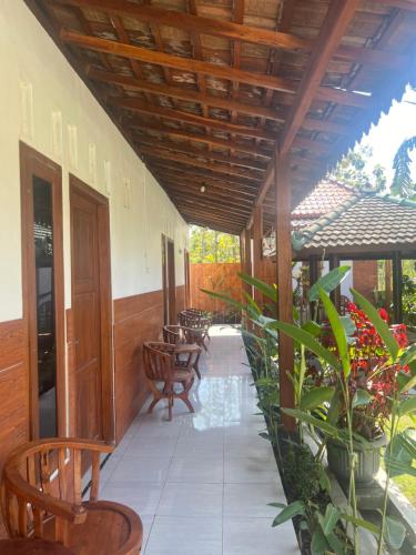 an outside patio with chairs and tables and plants at Homestay Joglo Beji in Gading