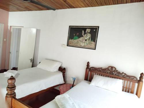 a bedroom with two beds and a picture on the wall at No 06 Veediya Bandara Lane Bahirawakanda in Kandy