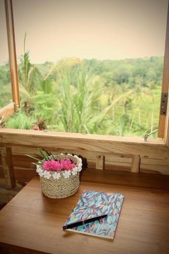 a table with a basket of flowers in front of a window at Dedari Lodge Jatiluwih Rice fields in Jatiluwih