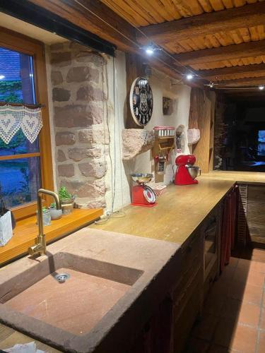- un comptoir de cuisine avec évier et une horloge murale dans l'établissement La maison aux quatres lavandes, à Neuve-Église