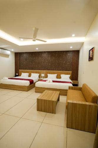 a hotel room with two beds and a couch at Grand View Residency in Nīleshwar