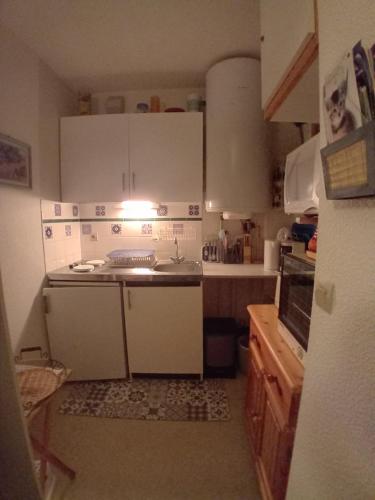 une petite cuisine avec des armoires blanches et un évier dans l'établissement Sur le GR10 et autres sentiers à Aulus-les-Bains, à Aulus-les-Bains