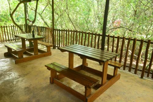 two picnic tables and benches on a porch with a fence at Toad Tree Cabins in Sodwana Bay