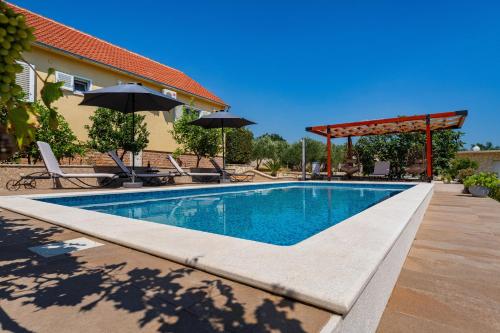a swimming pool with an umbrella next to a house at MY DALMATIA - Villa Sucic with private pool and mountain view in Obrovac
