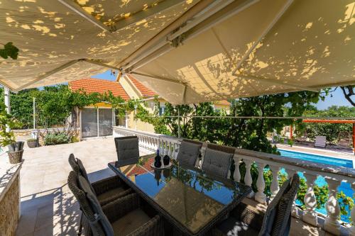 an outdoor dining table and chairs under an umbrella at MY DALMATIA - Villa Sucic with private pool and mountain view in Obrovac