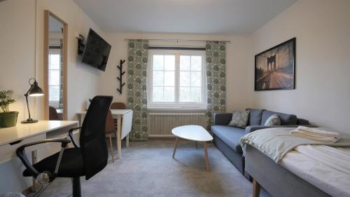 a small living room with a blue couch and a desk at Forenom Hostel Gothenburg Säve in Gothenburg