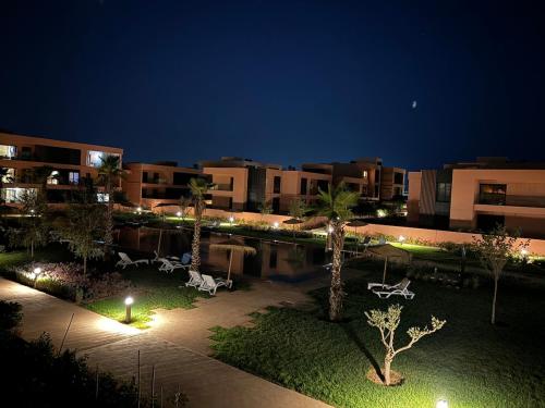 a courtyard with palm trees and lights at night at Domaine de Noria Isli 2 - Magnifique 2 chambres - Vue directe sur la piscine in Marrakech