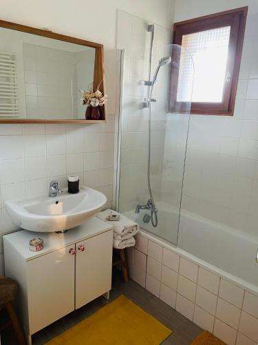 une salle de bain blanche avec un lavabo et une douche dans l'établissement Appartement situé en rez de jardin avec piscine privée en été, à Séez
