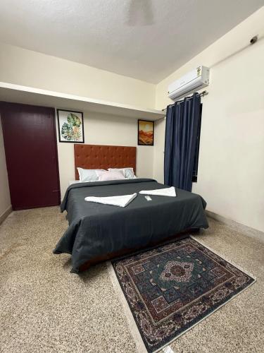 a bedroom with a large black bed with a rug at Kudla House in Mangalore