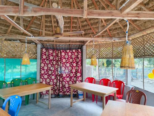 a dining room with tables and red chairs at sundarbon birds view cottage in Japur