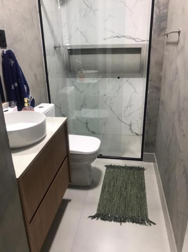 a bathroom with a sink and a shower and a rug at Apartamento aconchegante e espaçoso! in Guarujá