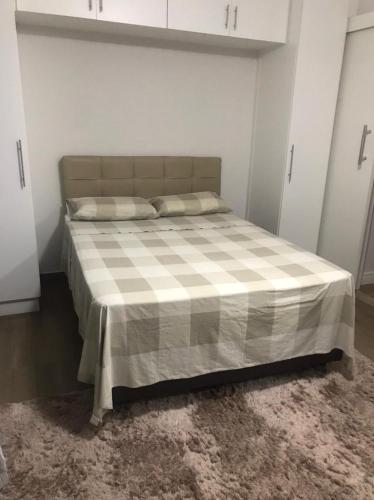 a bedroom with a bed with a checkered blanket at Apartamento aconchegante e espaçoso! in Guarujá