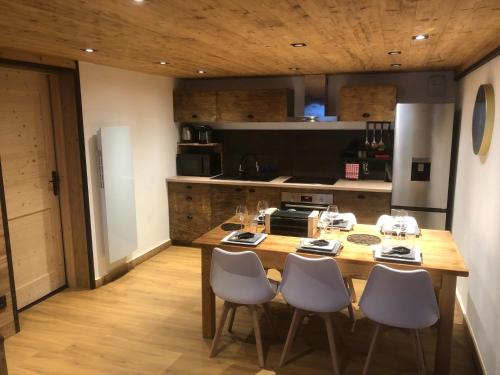 - une cuisine avec une table en bois et des chaises blanches dans l'établissement Appartement 6 personnes, à Bellecombe