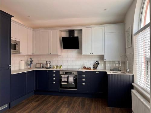 a kitchen with blue cabinets and white appliances at Stunning 2 bedroomed apartment on Allerton Road, Sleeps 4 in Liverpool