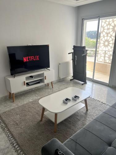 ein Wohnzimmer mit einem TV und einem Sofa in der Unterkunft Cozy Hideaway at Sousse in Port El-Kantaoui