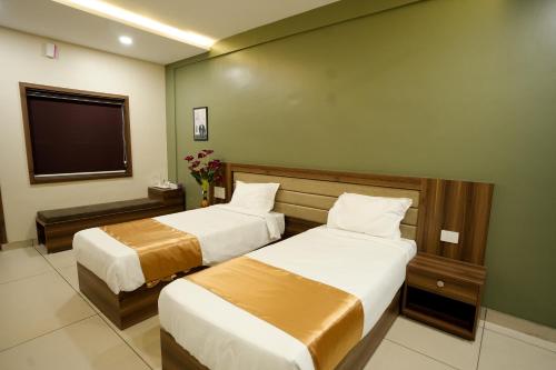 a hotel room with two beds and a television at Grand View Residency in Nīleshwar