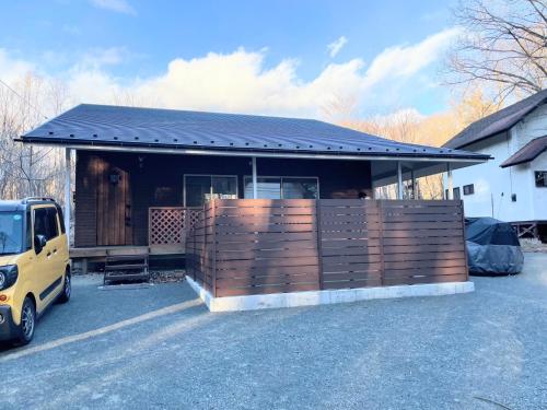a house with a fence in a parking lot at BBQ可 ワンちゃんok ロフト付き平屋を貸切で楽しむ特別な空間 ハチん家 in Hokuto