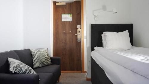 a bedroom with a bed and a couch and a door at Forenom Hostel Gothenburg Säve in Gothenburg