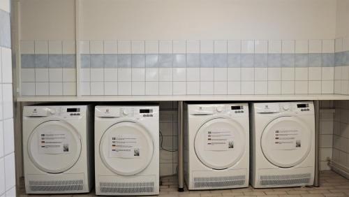 a row of four washing machines under a counter at Forenom Hostel Gothenburg Säve in Gothenburg