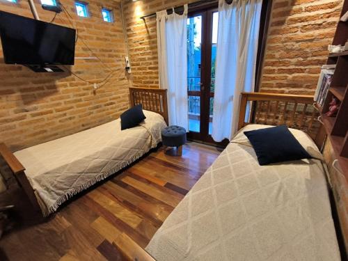 a bedroom with two beds and a tv on a brick wall at Hospedajes JUJUY in Palpalá