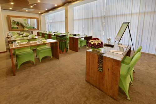 a large room with tables and green chairs at Whiz Hotel Malioboro Yogyakarta in Yogyakarta