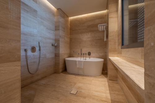 a bathroom with a white tub and a shower at SHIRVAN Hotel City Yard Jeddah in Jeddah