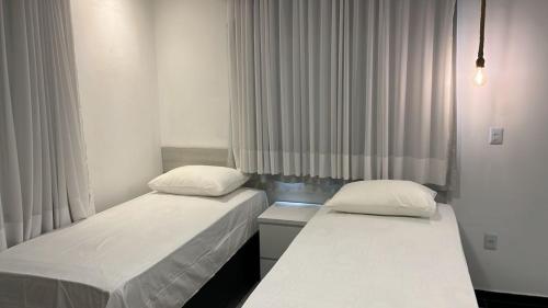 two beds in a small room with curtains at CARIBESSA BEIRA MAR CLUBE Aspep in João Pessoa