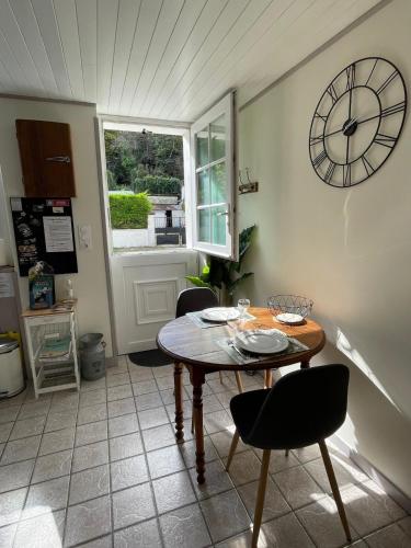une salle à manger avec une table et une horloge au mur dans l'établissement La Loge de Beauval maisonnette proche Zoo, à Seigy