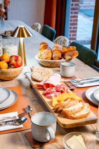 Una mesa de madera con pan y pasteles encima. en Les Charmes du Petit Pré, en Coulomby