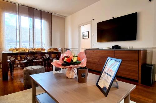 - un salon avec une télévision et une table fleurie dans l'établissement Le Terranova - Maison hypercentre, à Deauville