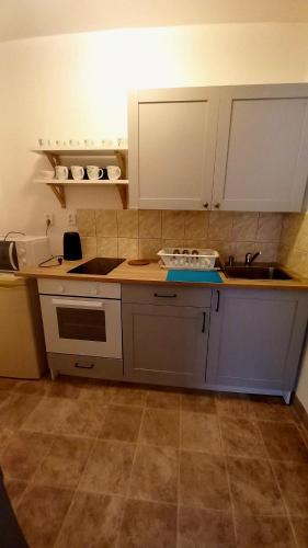 a kitchen with white cabinets and a sink and a counter at Apartmány Karlštejn in Karlštejn