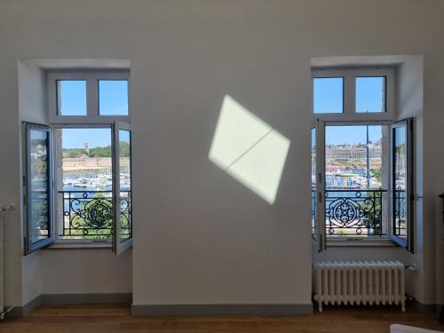 - deux fenêtres dans une chambre avec vue sur la ville dans l'établissement Maison Le Rose, à Concarneau