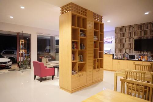 een boekenplank in een kamer met een tafel en stoelen bij Chompu Nakarin Apartment in Trang