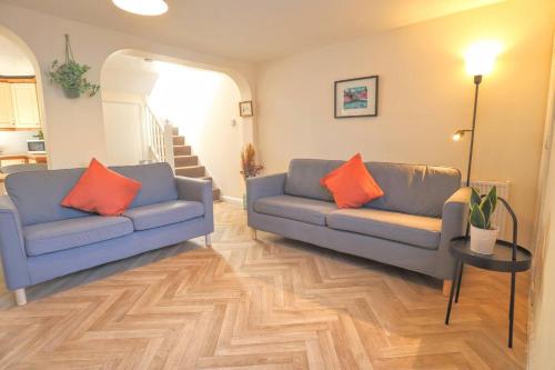 a living room with two blue couches and orange pillows at 4 bed home 3 mins from harbour + sandy beach in Kent