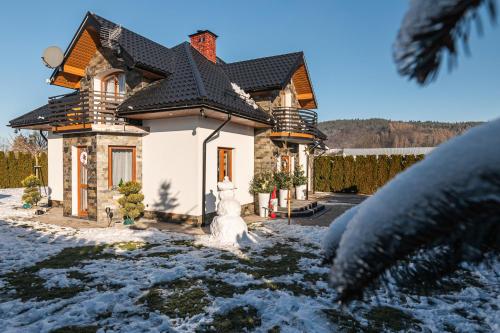 a house with a snowman in front of it at Dream Holiday z Sauna i jacuzzi Lovely Krynica Zdrój in Florynka